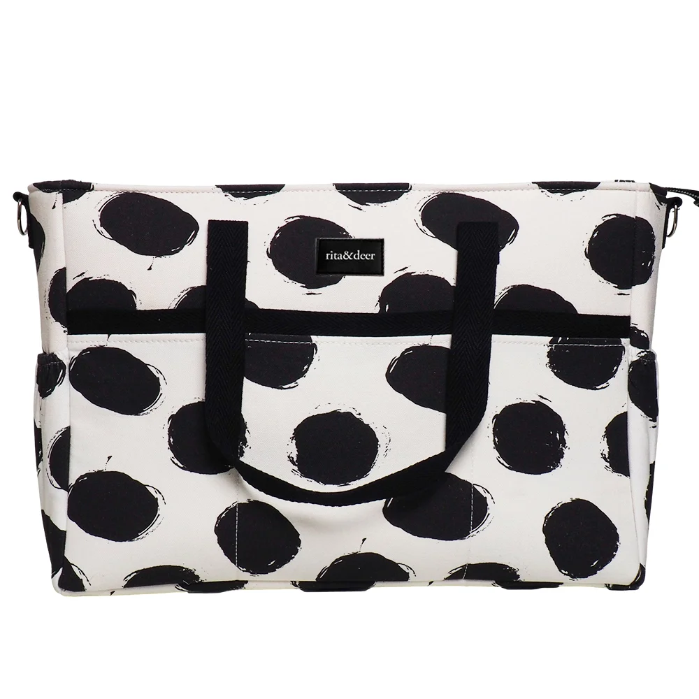 bolso de carro gemelar de motas negras y fondo en color blanco cococnut milk, Un original y moderno estampado para esta bolsa gemelar.